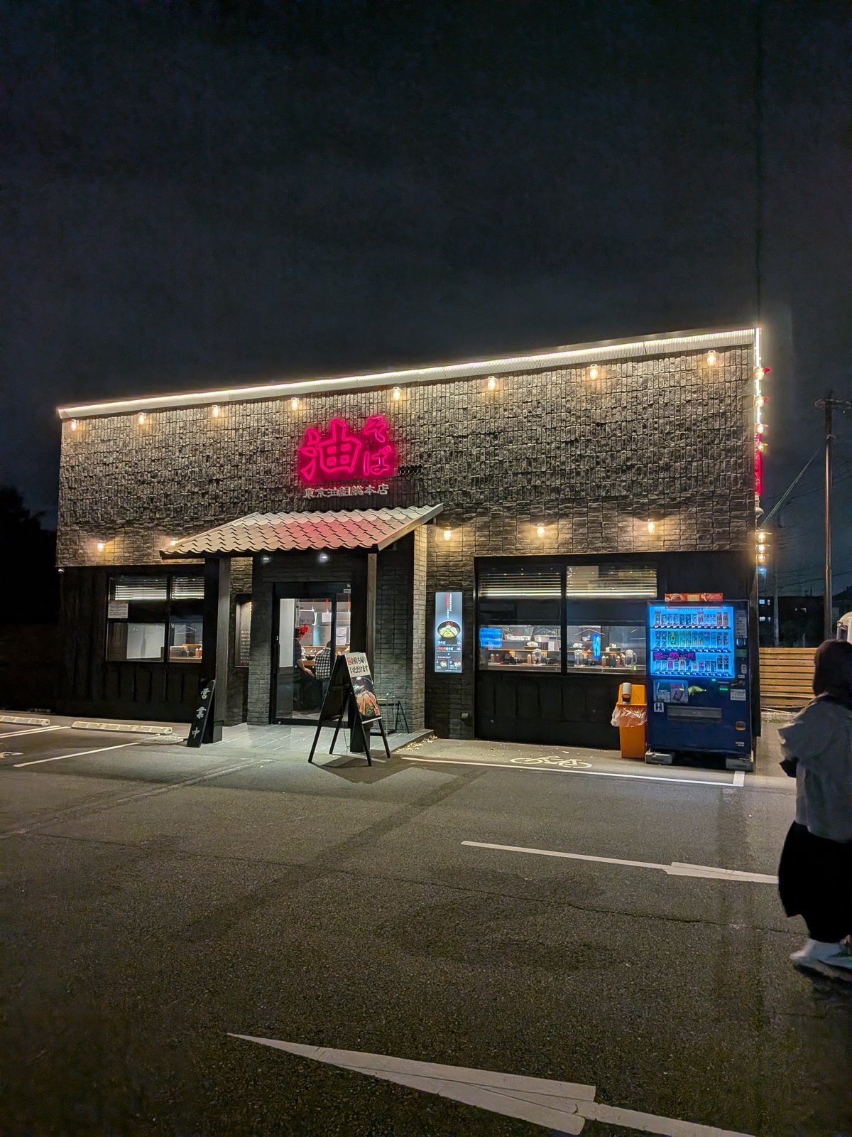 東京油組総本店 立川若葉町組の外観。五日市街道沿いの店舗でピンク色の「油そば」ネオンサインが目印
